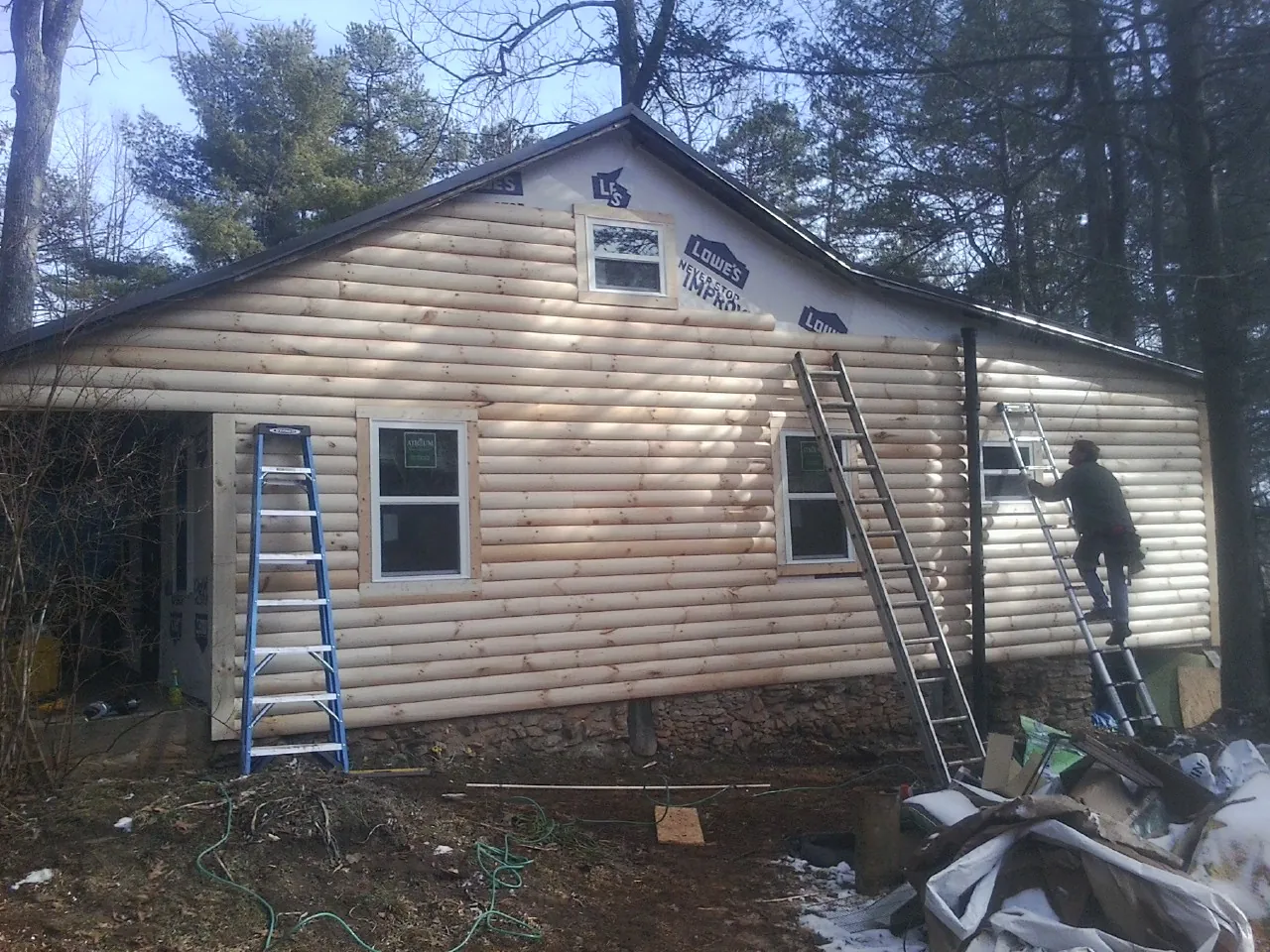 Ladders set against fresh log siding during an exterior remodel in Deerfield